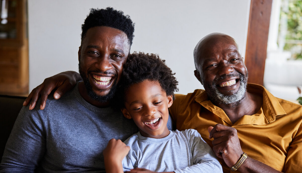 A family of three sitting on a couch and laughing.