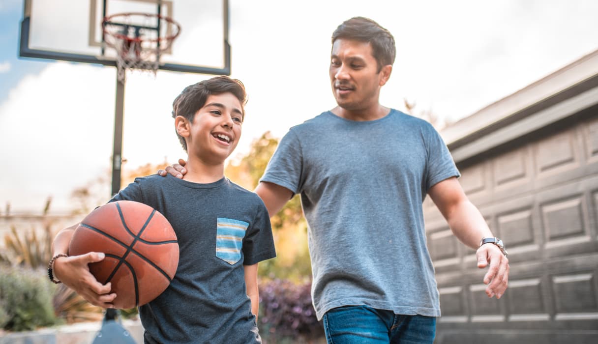 A father and son with a basketball in their driveway